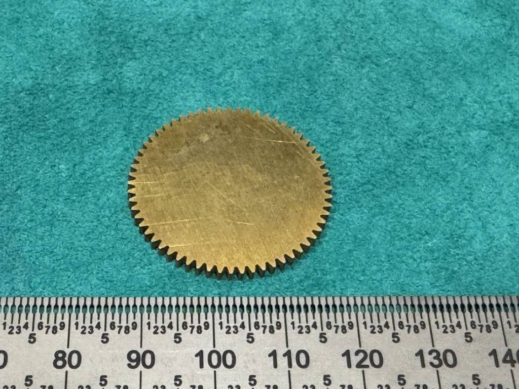 Fine brass gear beside a ruler