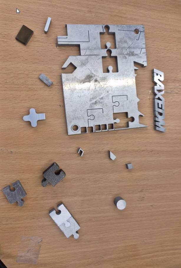 Sample plate with small cut pieces and a BAXEDM logo