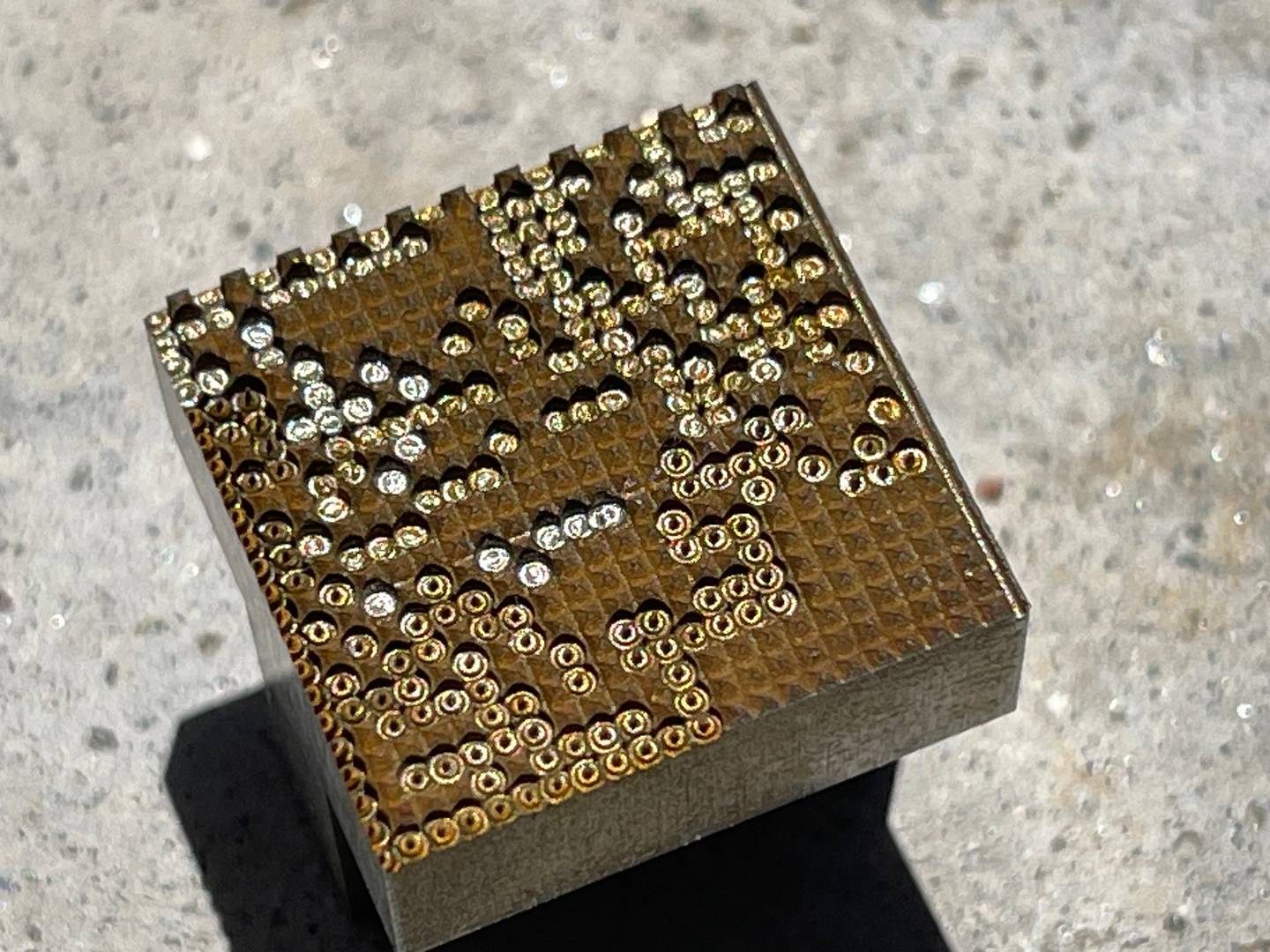 Metal block covered in a dense pattern of small holes